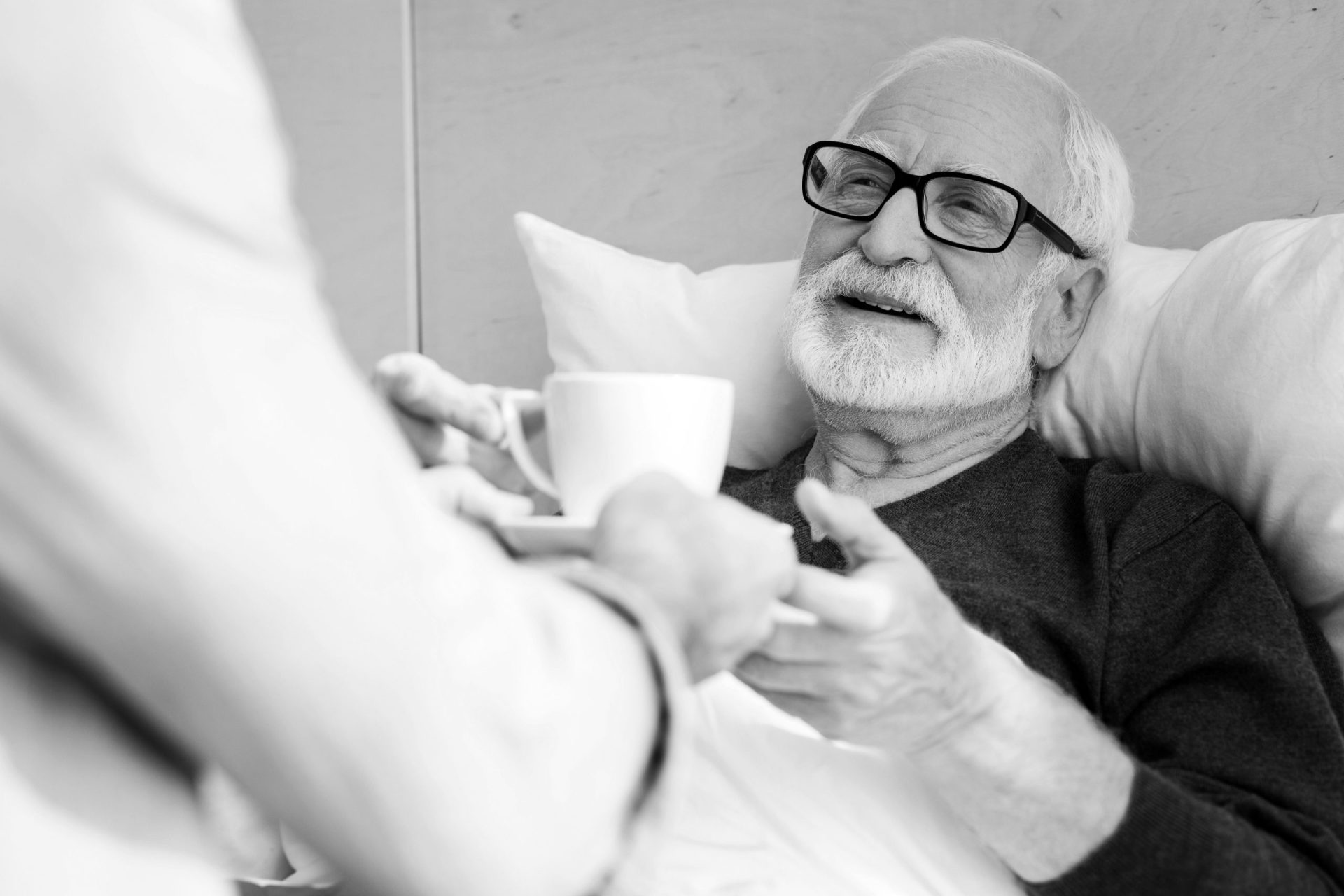 Older man being offered a hot drink